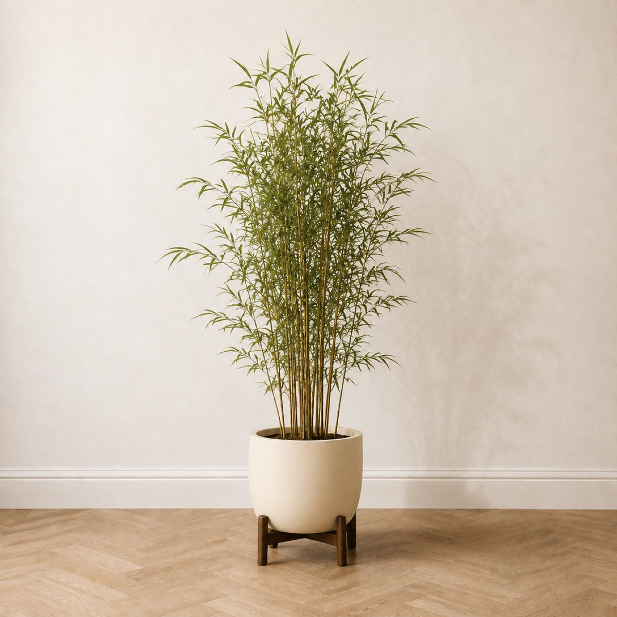 Bambou artificiel 150 cm dans un pot crème posé sur un pied en bois, sur un parquet en chêne à bâtons rompus