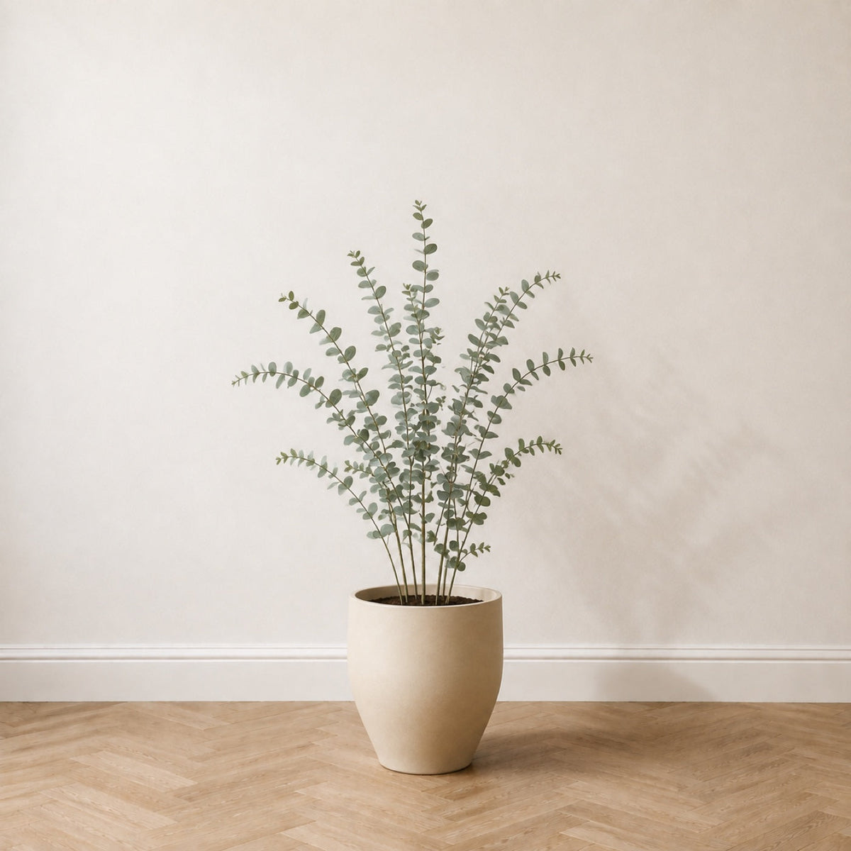 Eucalyptus artificiel 130 cm dans un pot en céramique crème, sur un parquet en chêne à bâtons rompus